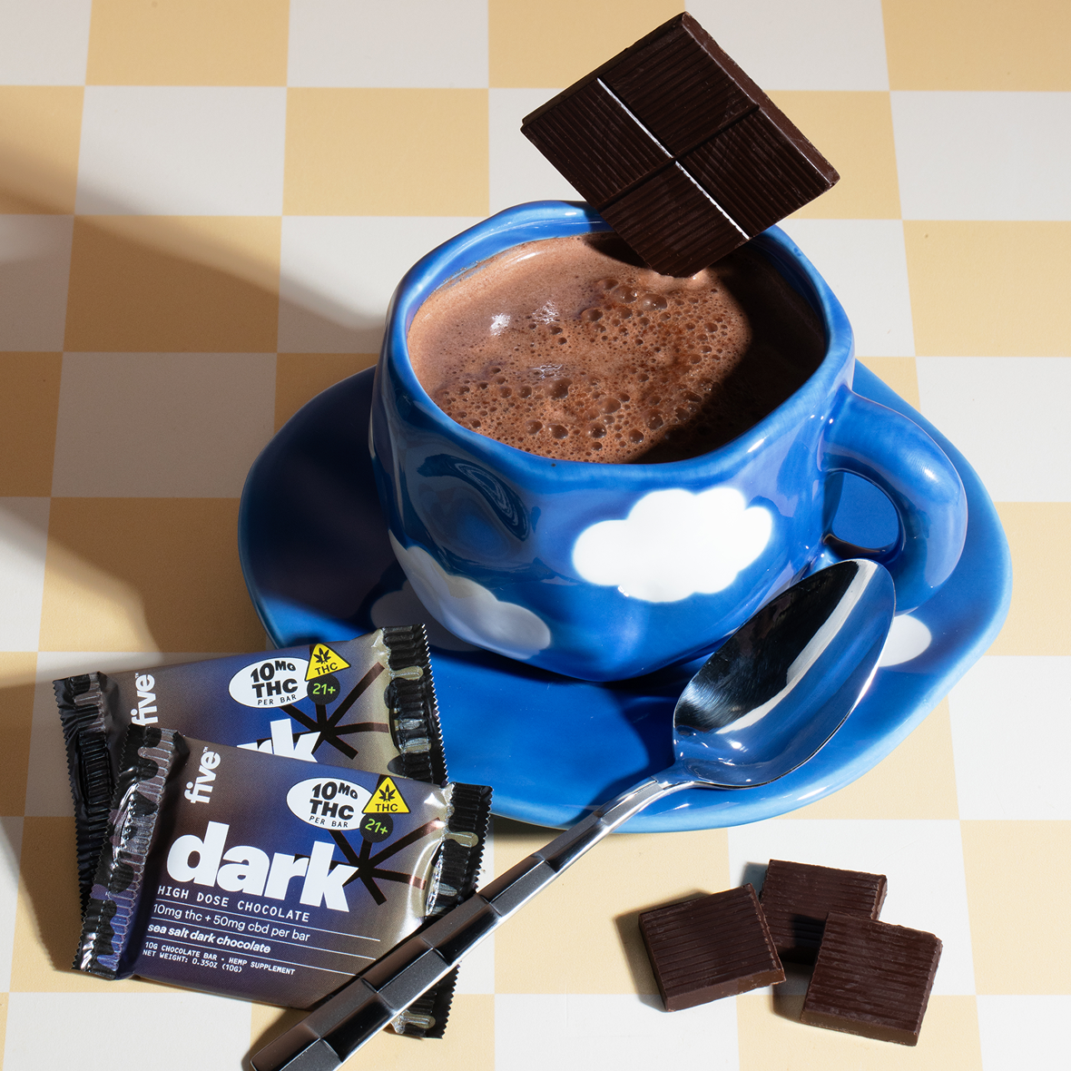 A cup of hot chocolate with a spoon and chocolate bars.