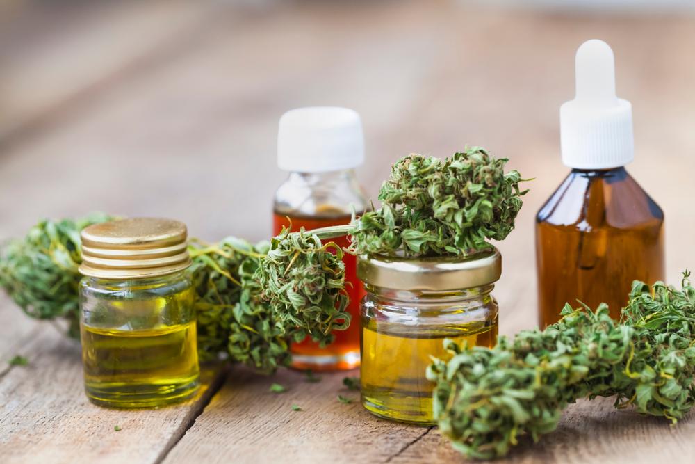 Cannabis buds and small bottles of cannabis oil on a wooden surface, illustrating THC-O products.