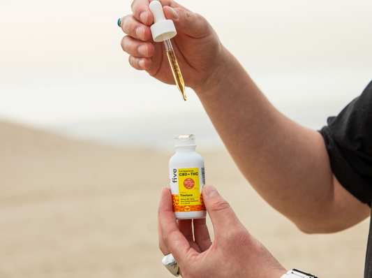 Person holding a dropper above a white bottle labeled 'five Full Spectrum CBD + THC Citrus Tincture 1500mg CBD / Bottle Hemp-Derived Supplement 1 fl. oz. (30 ml)'