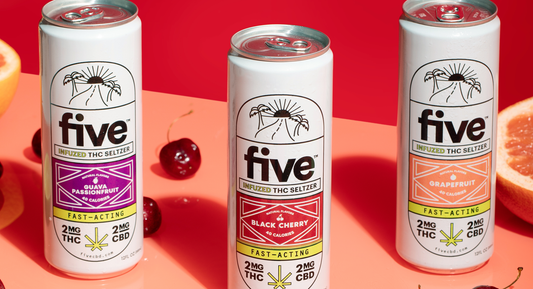 Front view of three Five THC seltzer cans showing flavor labels and 2mg THC 2mg CBD on pink background with cherries and grapefruit