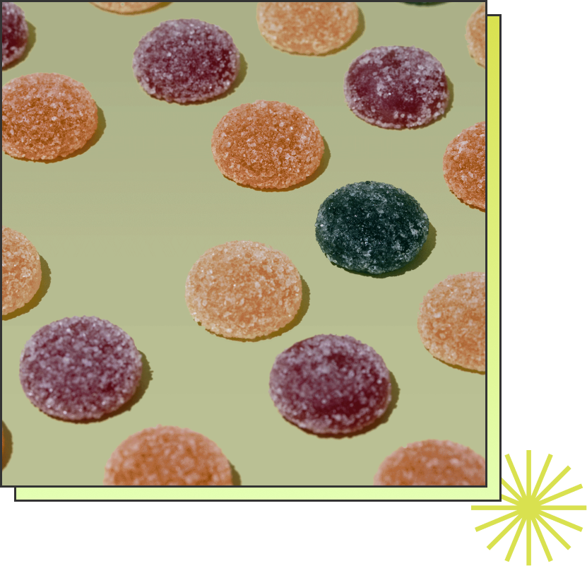 Colorful sugar-coated round gummy candies in orange, purple, and black on a light green background.
